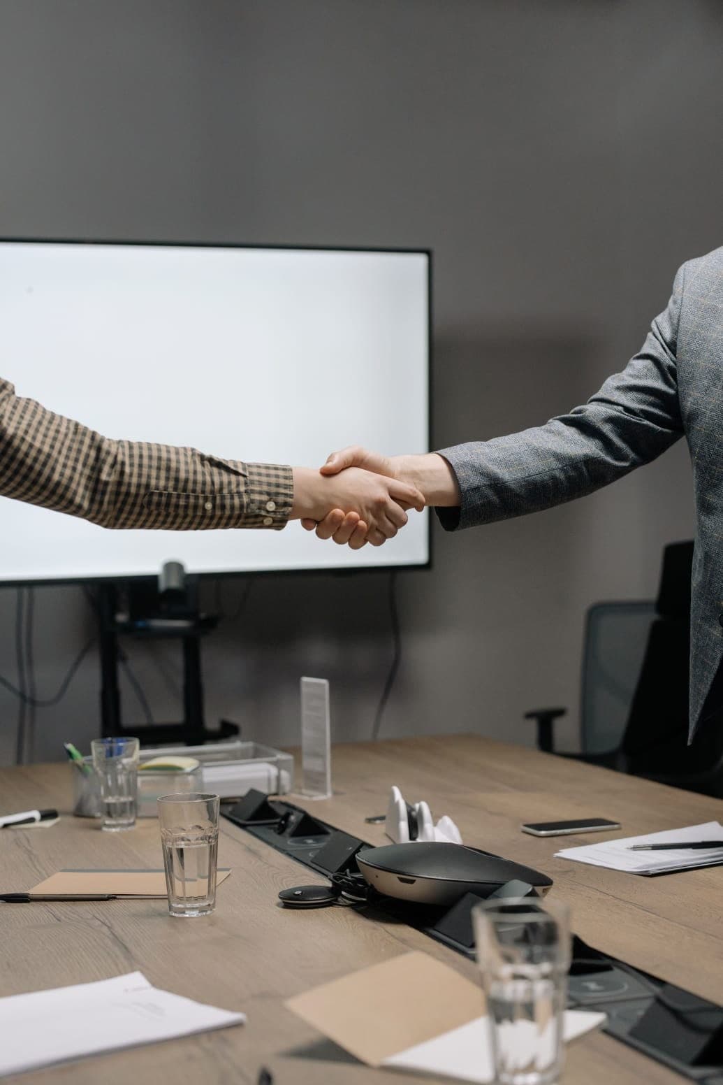 Aperto de mãos selando uma parceria em sala de reunião