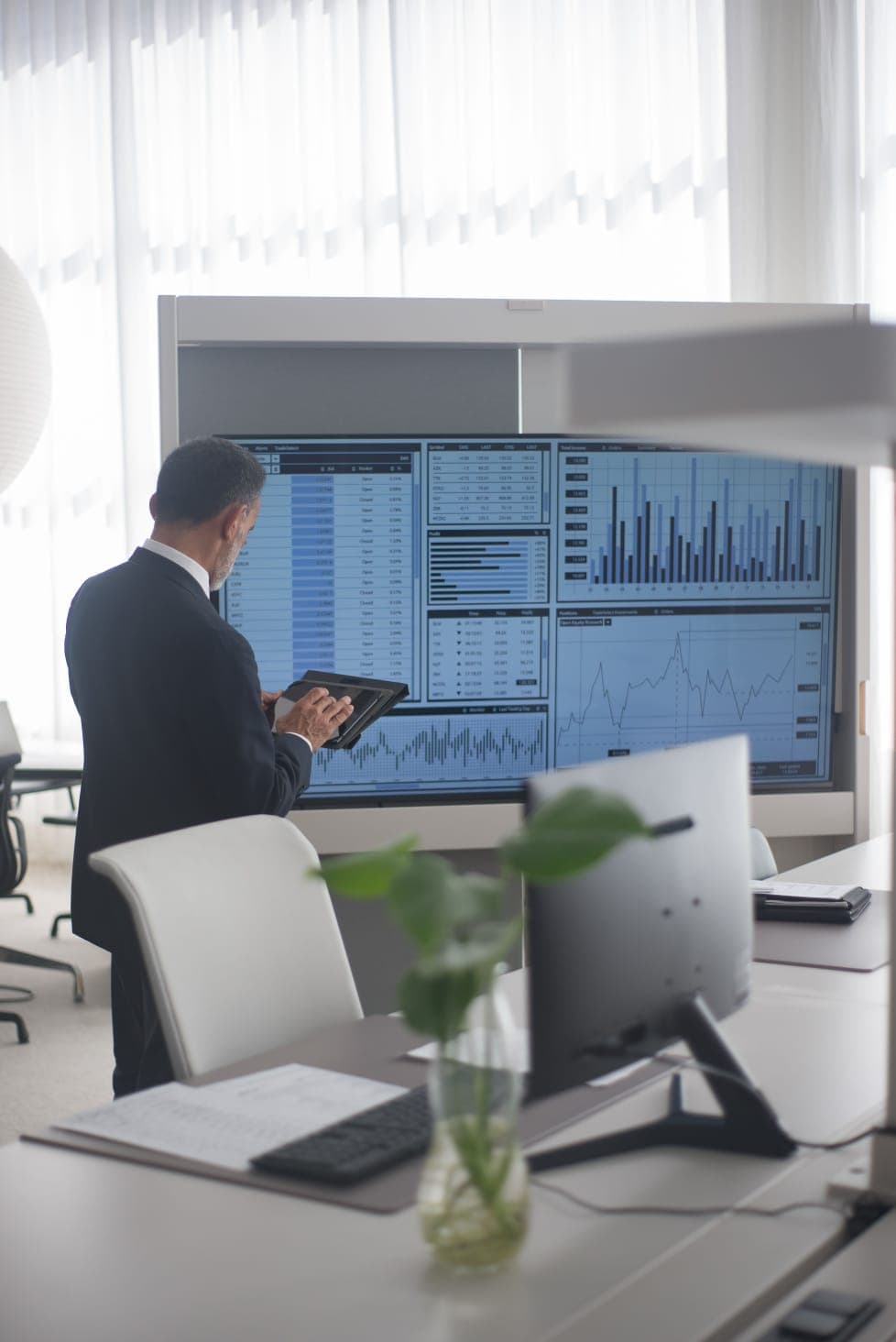Gestor analisando painéis de indicadores do ERP em uma tela grande no escritório