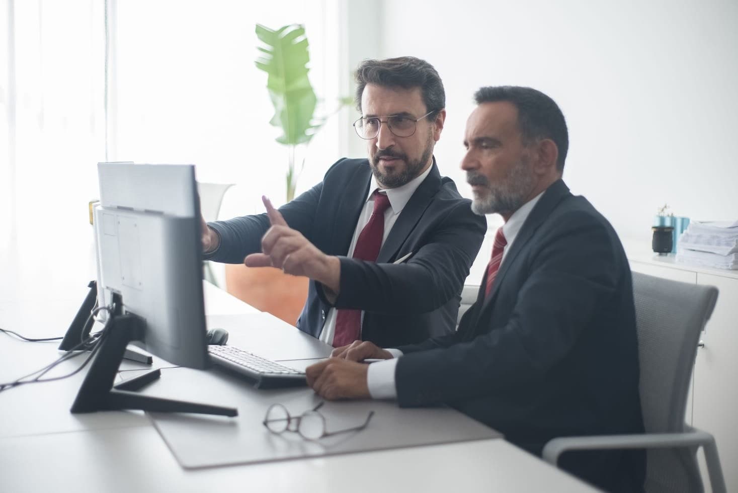 Dois profissionais analisando um sistema juntos em frente ao computador